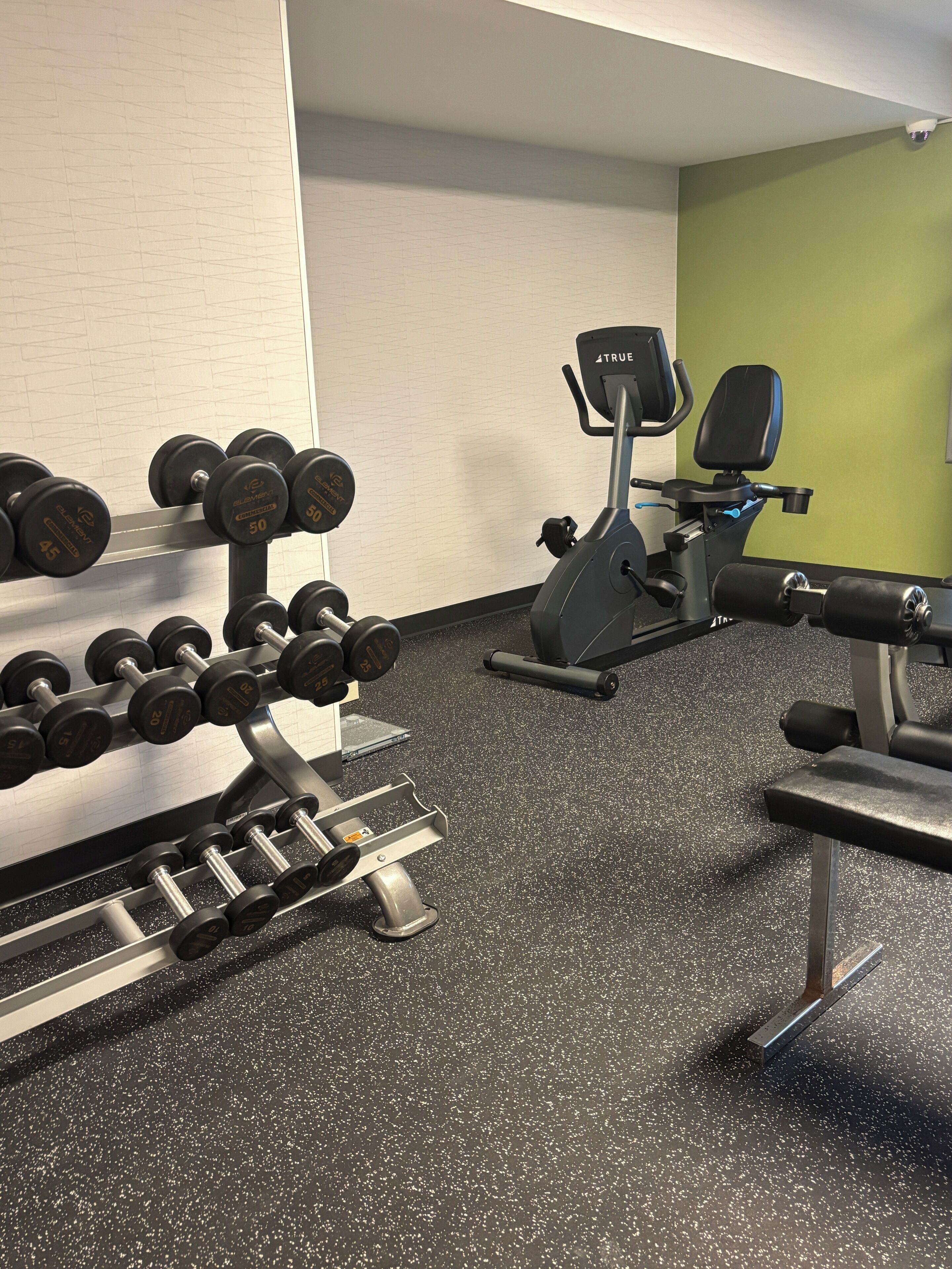 A gym with weightlifting equipment, including dumbbells and a bench.