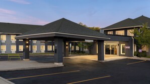 A hotel entrance with a covered waiting area, a parking lot, and a building with a 'spark' sign. - Spark by Hilton Toronto Mississauga (Mississauga)