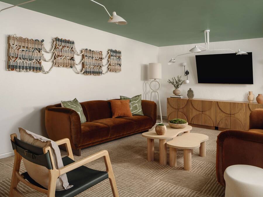 A modern living room with a brown sofa, a wooden chair, a coffee table, and a TV mounted on the wall.