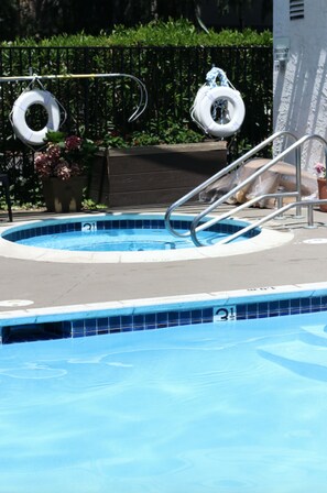 A swimming pool with a metal ladder and two life rings hanging above it.