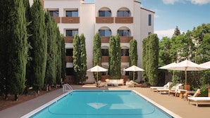 A poolside area with lounge chairs, umbrellas, and tall trees. - Hotel Avante - JDV by Hyatt (Mountain View)