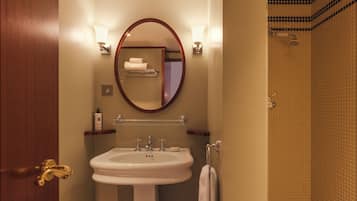 Un baño con lavamanos blanco, un espejo y zona de ducha.