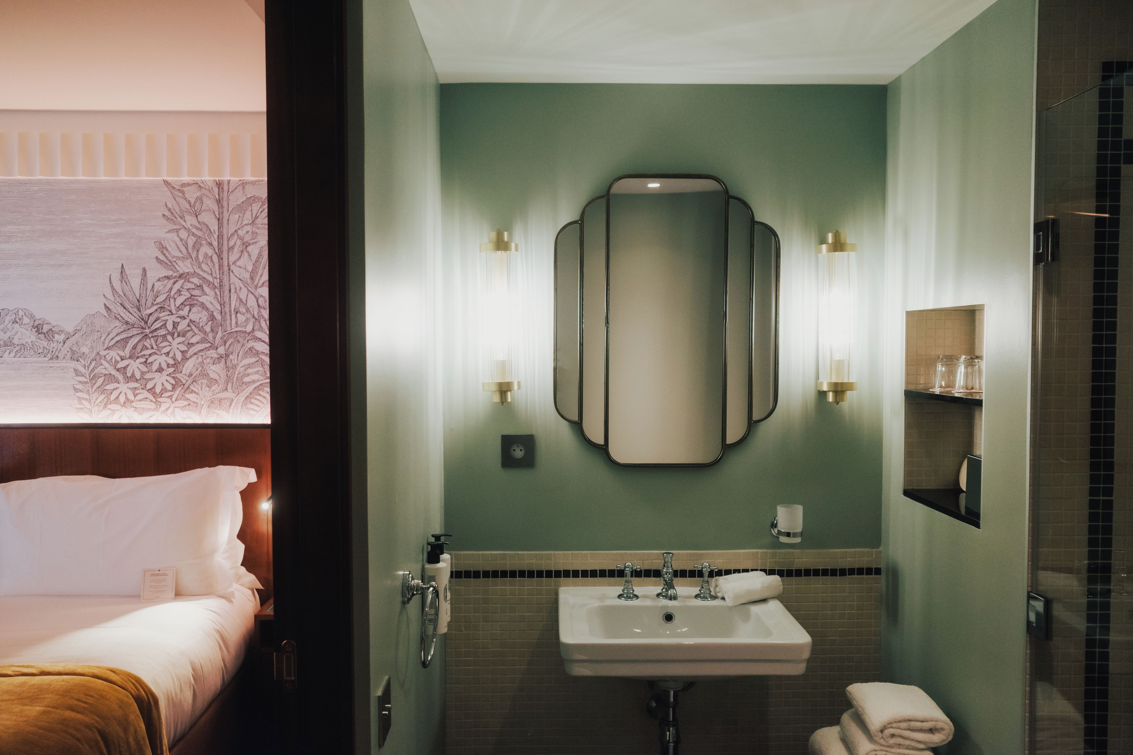 Una habitación de hotel con cama, baño con lavamanos y espejo.