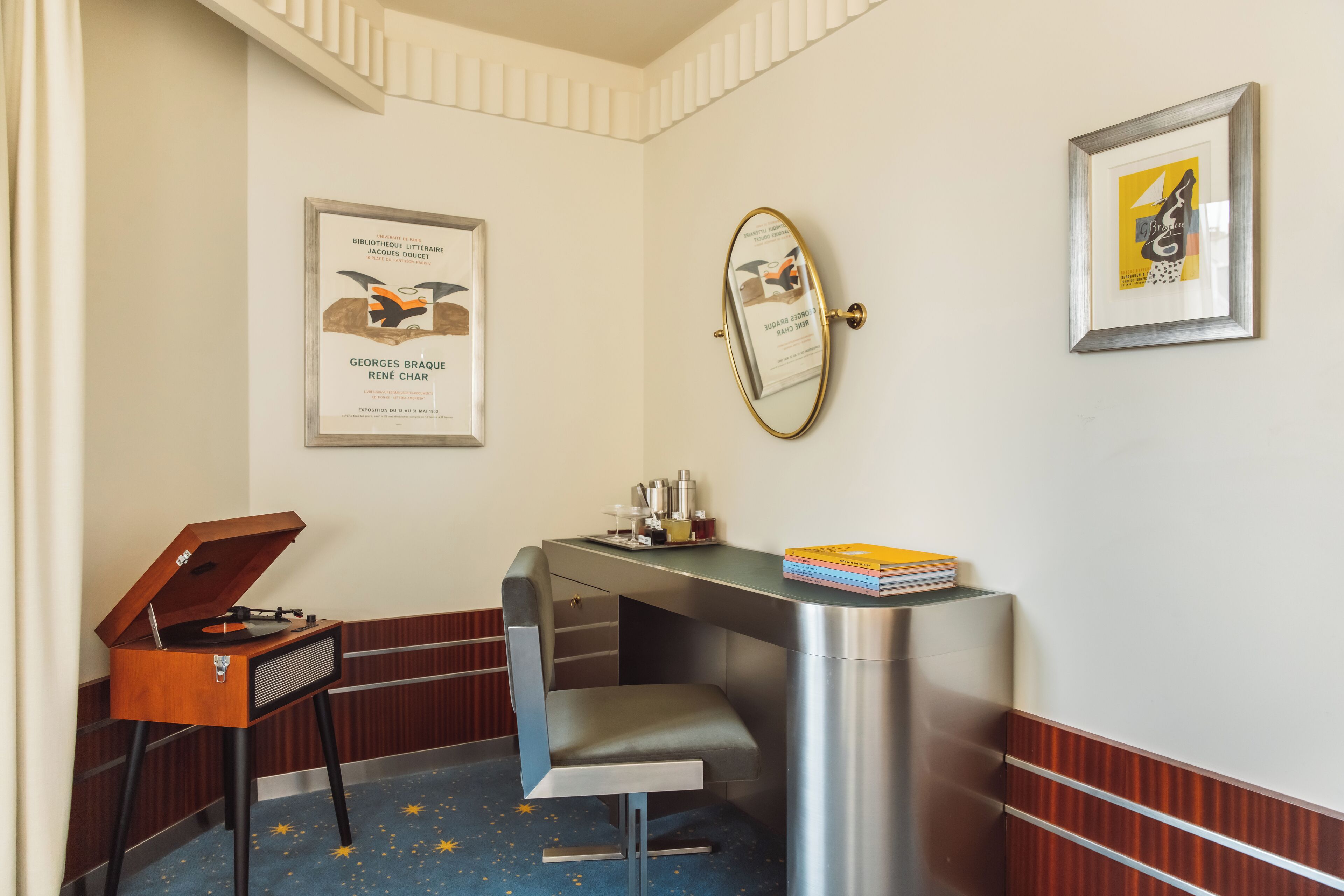 Une pièce comprenant un bureau, une chaise, un miroir et des œuvres d’art encadrées accrochées aux murs.