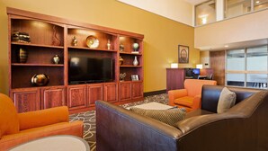 A hotel lobby with a wooden entertainment center, leather sofas, and a flat-screen TV. - Best Western Executive Inn Kenosha/Pleasant Prairie (Kenosha)