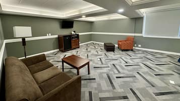 Una sala de estar con sofá, mesa de centro, alfombra estampada, aparador y televisor.