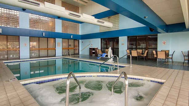 An indoor swimming pool with a hot tub, surrounded by seating areas and a tiled floor. - Best Western Executive Inn Kenosha/Pleasant Prairie (Kenosha)