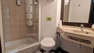 A bathroom with a glass-enclosed shower, a toilet, a sink with a mirror, and a checkered floor.