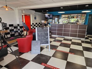 A café with a checkered floor, a red counter, and chalkboards displaying menu items. - KYRIAD MONTLUCON - Saint Victor (Saint-Victor)