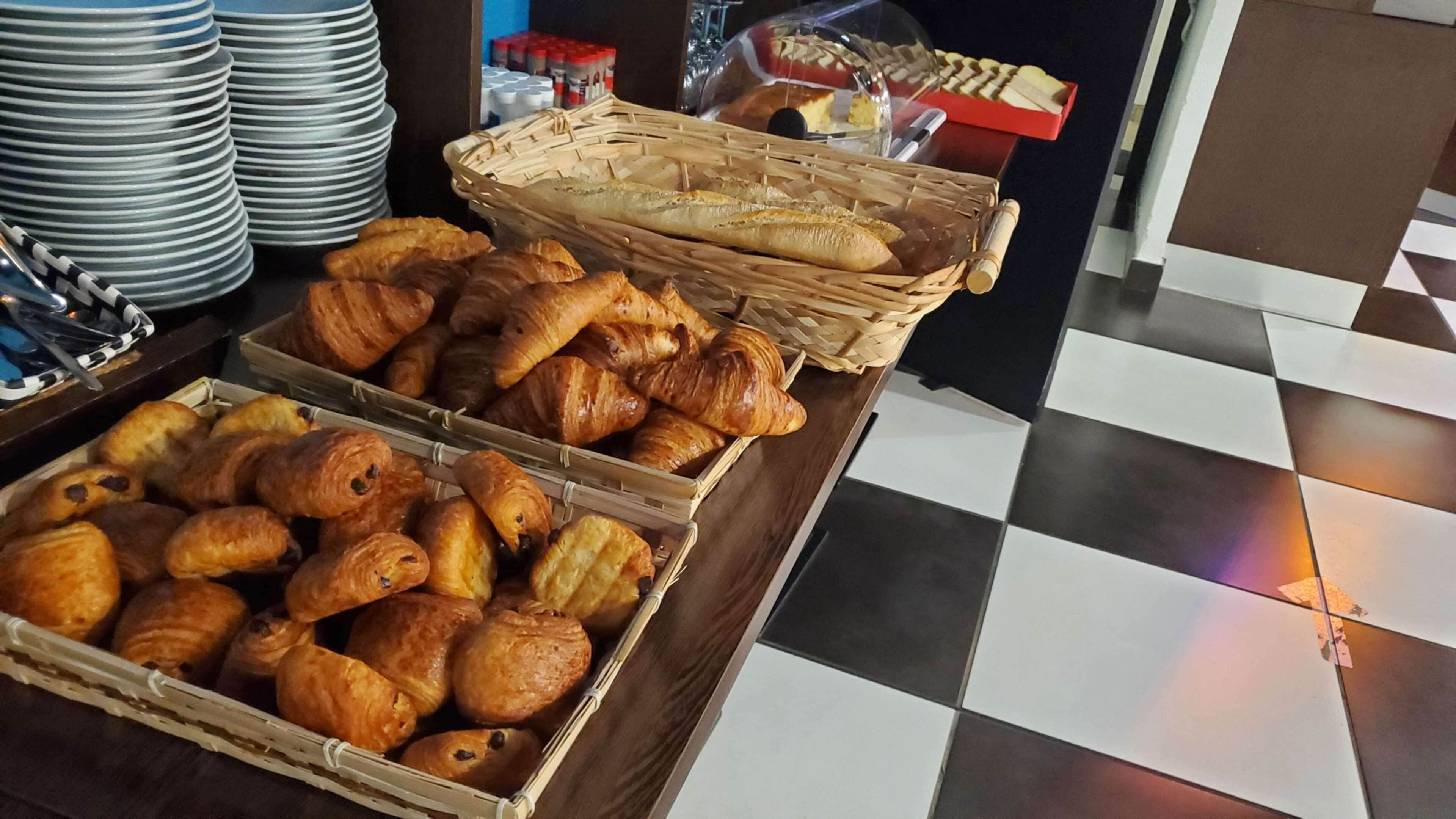 Una exhibición de panadería variada, con croissants y barras, dispuesta en cestas de mimbre y cajas de madera.