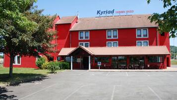 A red building with a sign reading "Kyriad Design Enzo".
