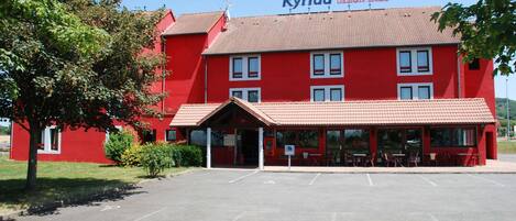 Un edificio rojo con un cartel que dice "Kyriad Design Enzo".