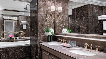 Un baño moderno con dos lavabos, paredes de mármol y un espejo grande.
