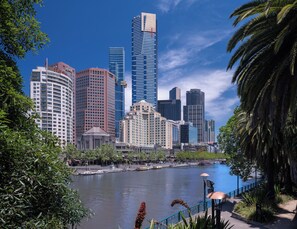 A city skyline with modern high-rise buildings, a river, and a bridge.