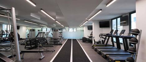 Un gimnasio moderno con cintas de correr, máquinas de pesas y mancuernas.