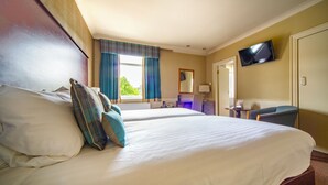 Une chambre d’hôtel avec deux lits, un téléviseur fixé au mur et un bureau avec une chaise.