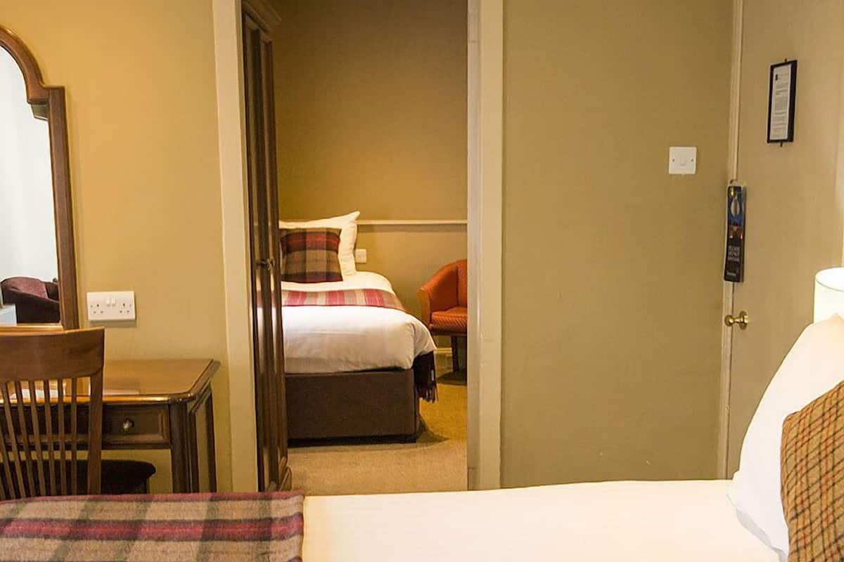 A hotel room with two beds, a desk, and a chair.