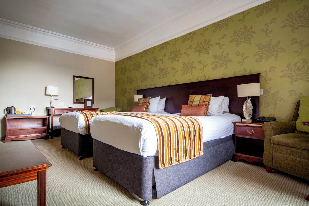 A hotel room with two beds, a desk, a chair, and a nightstand.