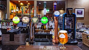 Un bar doté de plusieurs robinets à bière, dont un pour la Guinness, et un verre de bière posé sur un sous-verre en bois.