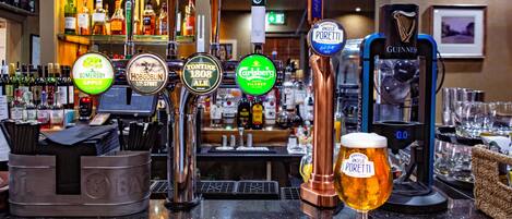 A bar with multiple beer taps, a Guinness tap, and a glass of beer on a wooden bar mat.