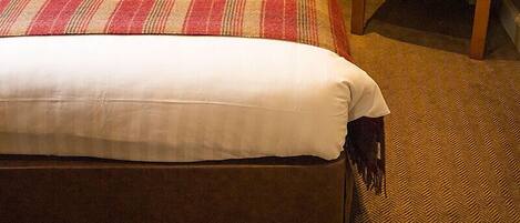 Une chambre d’hôtel avec un lit, une chaise et un sol recouvert de moquette.