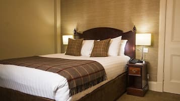 Una habitación de hotel con una cama grande, dos lámparas de noche, una mesita de noche y una puerta.