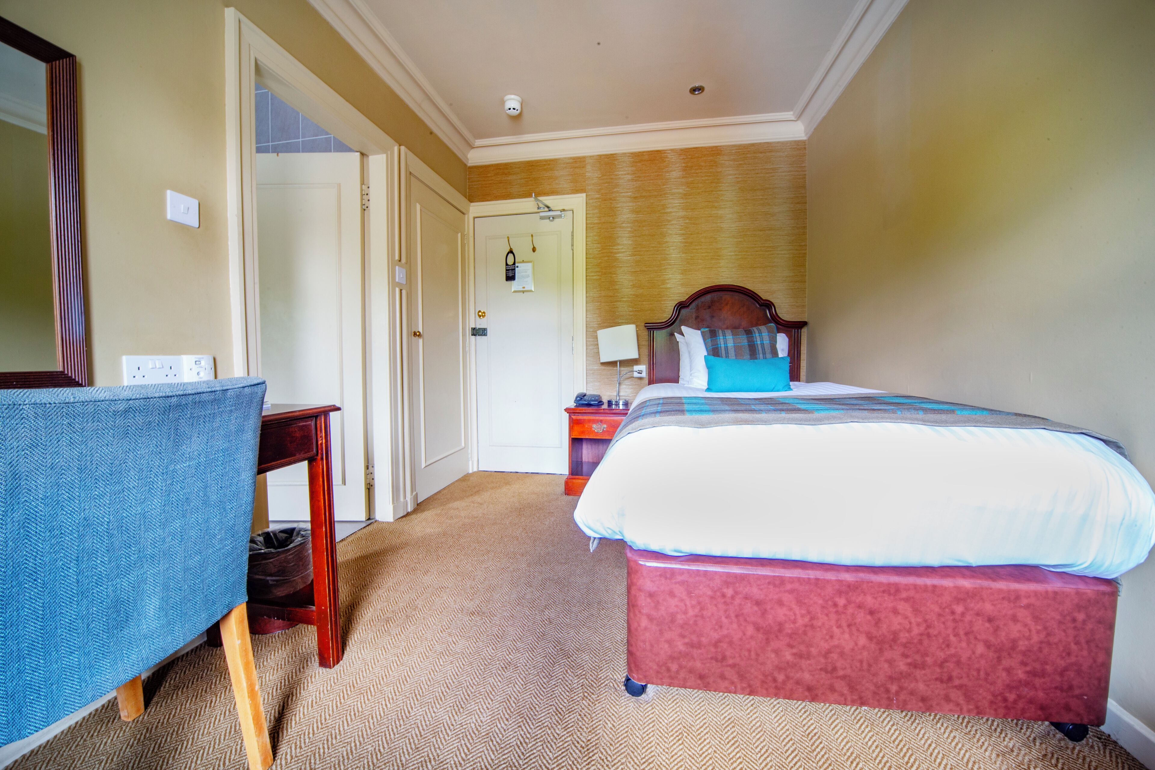 A hotel room with a bed, a desk, and a chair.