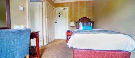 A hotel room with a bed, a desk, and a chair.