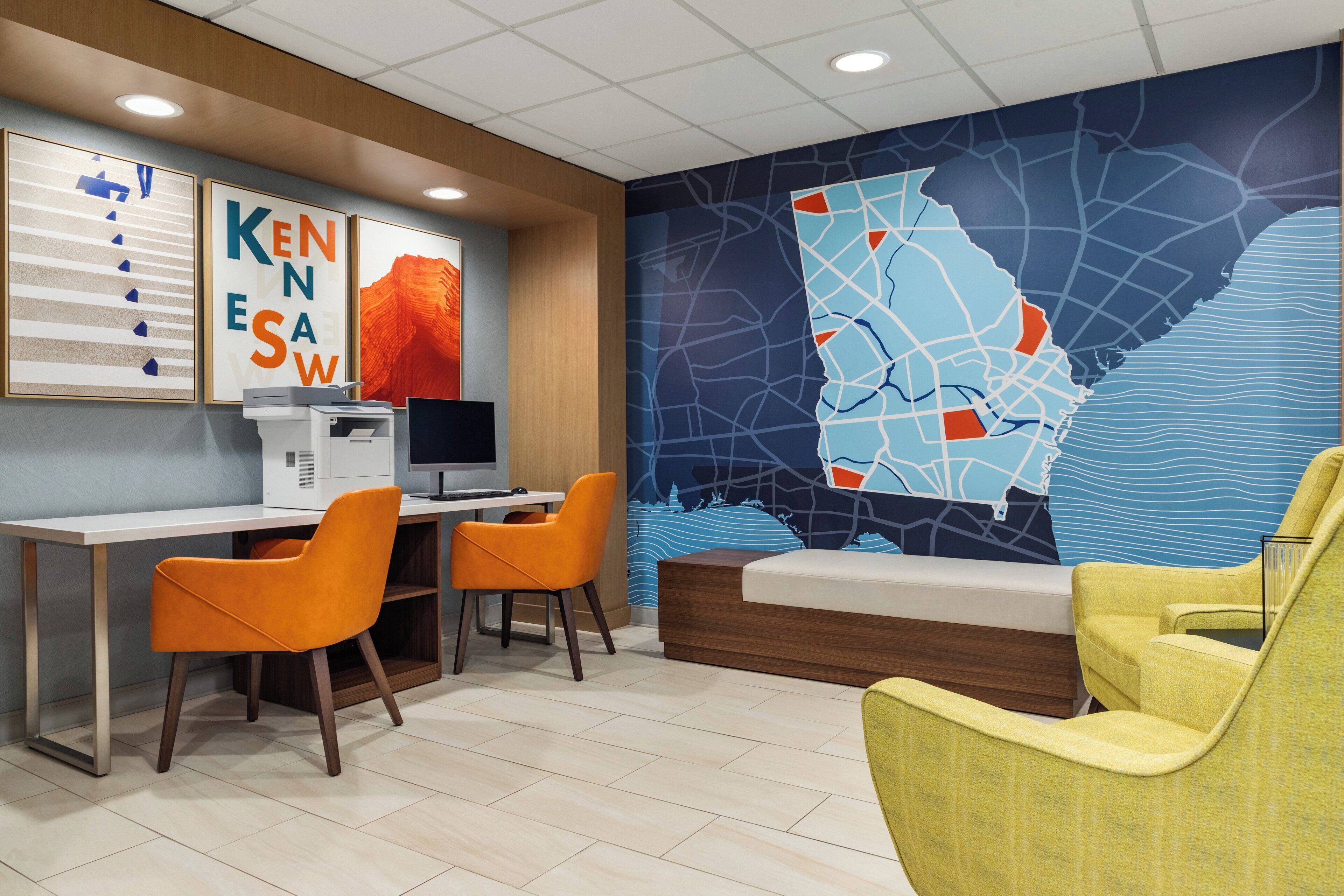 A modern office space with a desk, two chairs, a bed, and a large wall map.