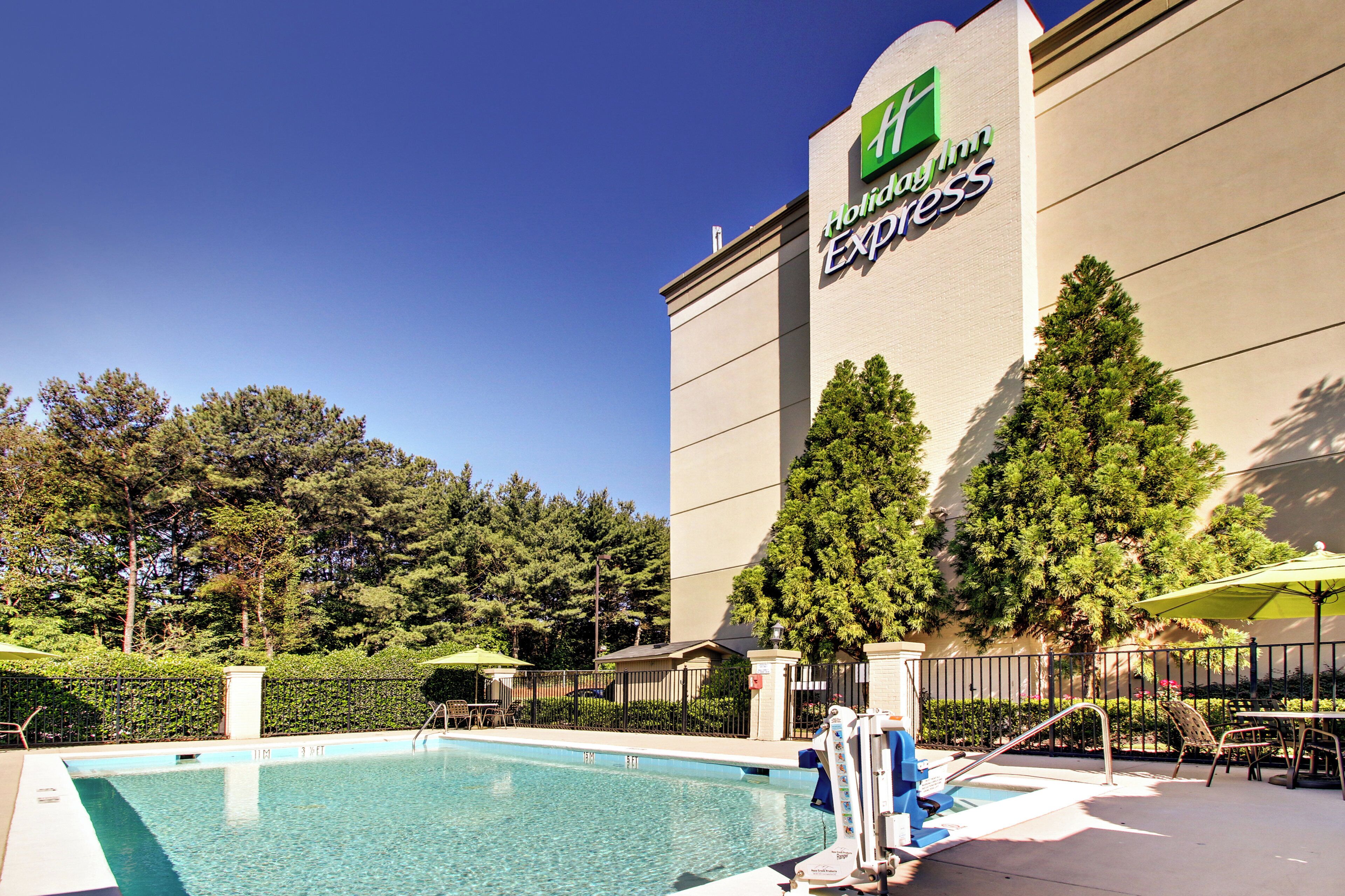 A hotel with a swimming pool, outdoor seating, and a large sign for Holiday Inn Express.