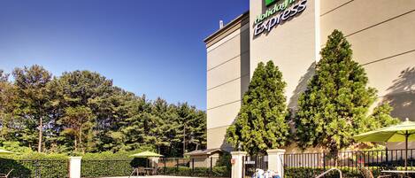 A hotel with a swimming pool, outdoor seating, and a large sign for Holiday Inn Express.