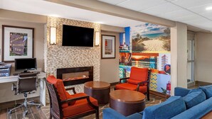 A hotel lobby with a fireplace, seating area, and artwork on the walls. - Clarion Pointe Racine - Mount Pleasant (Mount Pleasant)