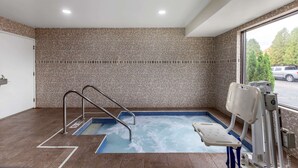 A small indoor pool with a blue tiled edge, a metal ladder, and a pool chair. - Clarion Pointe Racine - Mount Pleasant (Mount Pleasant)