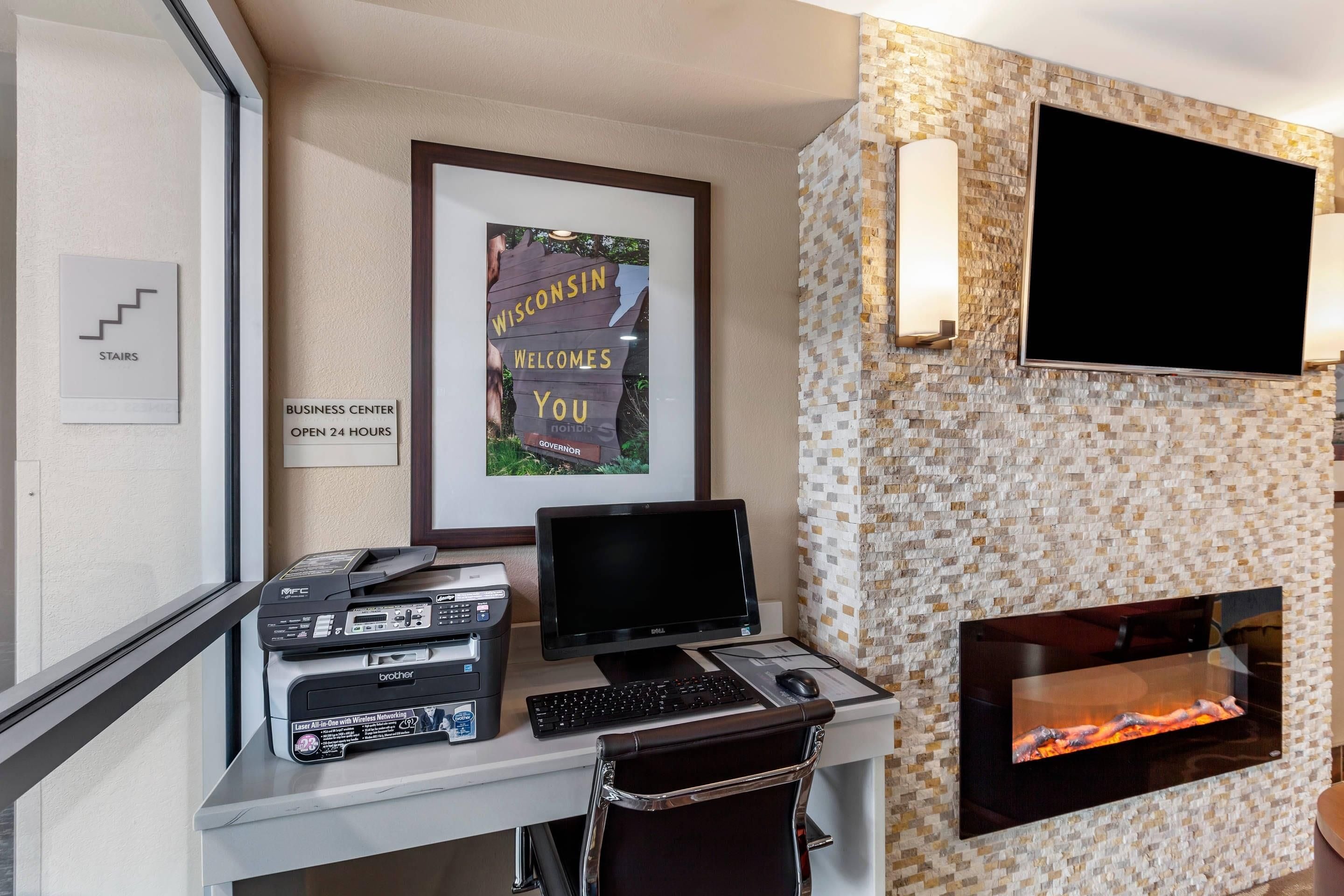Ein Business-Center mit Flachbildfernseher, Kamin und Schreibtisch inklusive Computer und Drucker.