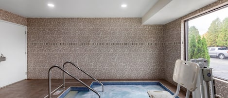 A hot tub area with a pool, a wheelchair, and a view of the outside.