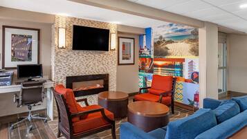 A hotel lobby with a fireplace, seating area, and a flat-screen TV.