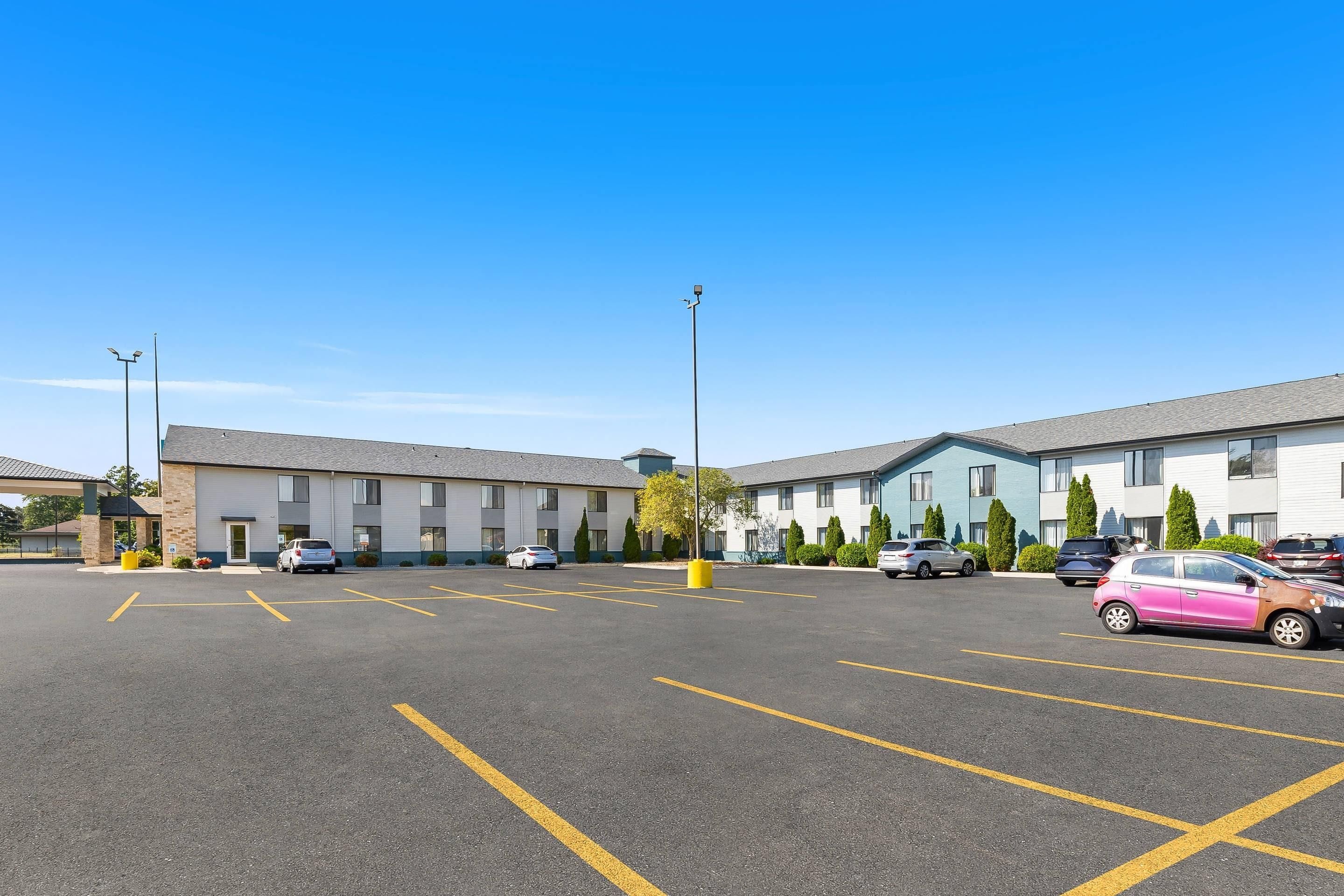 A parking lot with marked spaces, a building with a flat roof, and a clear blue sky.