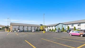 A parking lot with marked spaces, a building with a flat roof, and a clear blue sky.