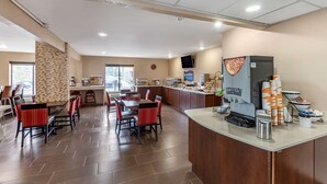 A hotel dining area with a buffet setup, a coffee machine, and a TV mounted on the wall. - Clarion Pointe Racine - Mount Pleasant (Mount Pleasant)