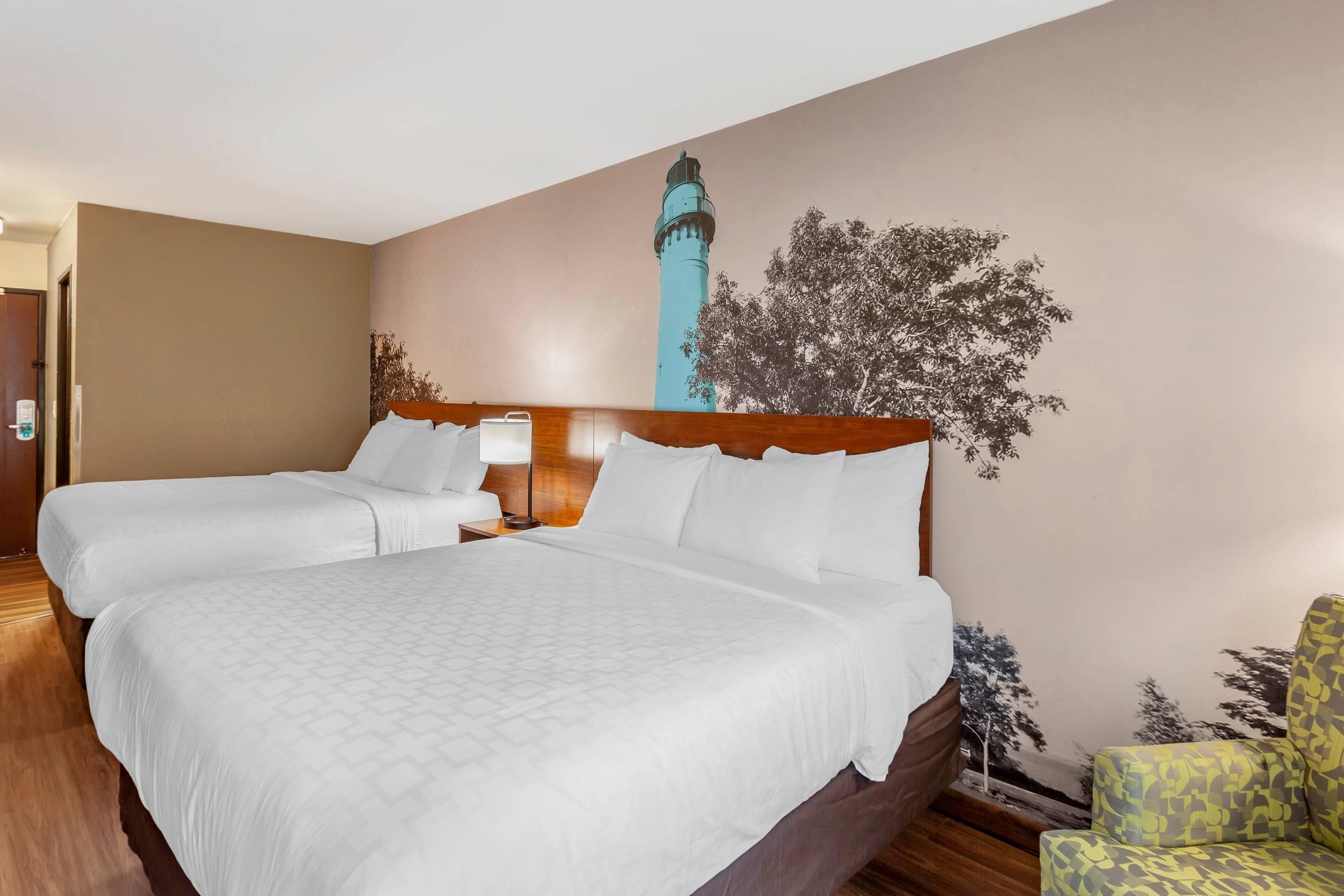 A hotel room with a large bed, a wooden headboard, and a wall mural.