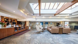 A spacious lobby with a reception desk, seating area, and a skylight.