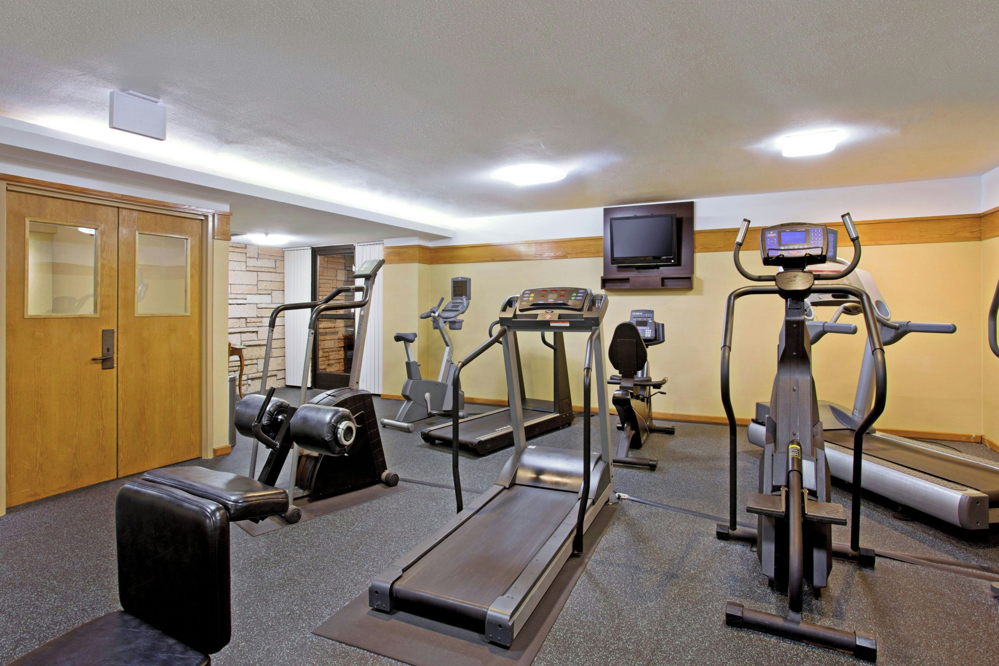 Un gimnasio con cintas de correr, elípticas y una bicicleta estática.