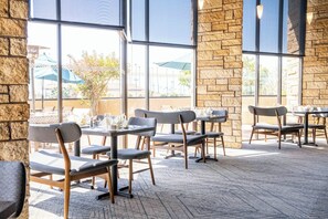 An indoor dining area with stone walls, large windows, and modern chairs. - Four Points by Sheraton Ventura Harbor Resort (Ventura)