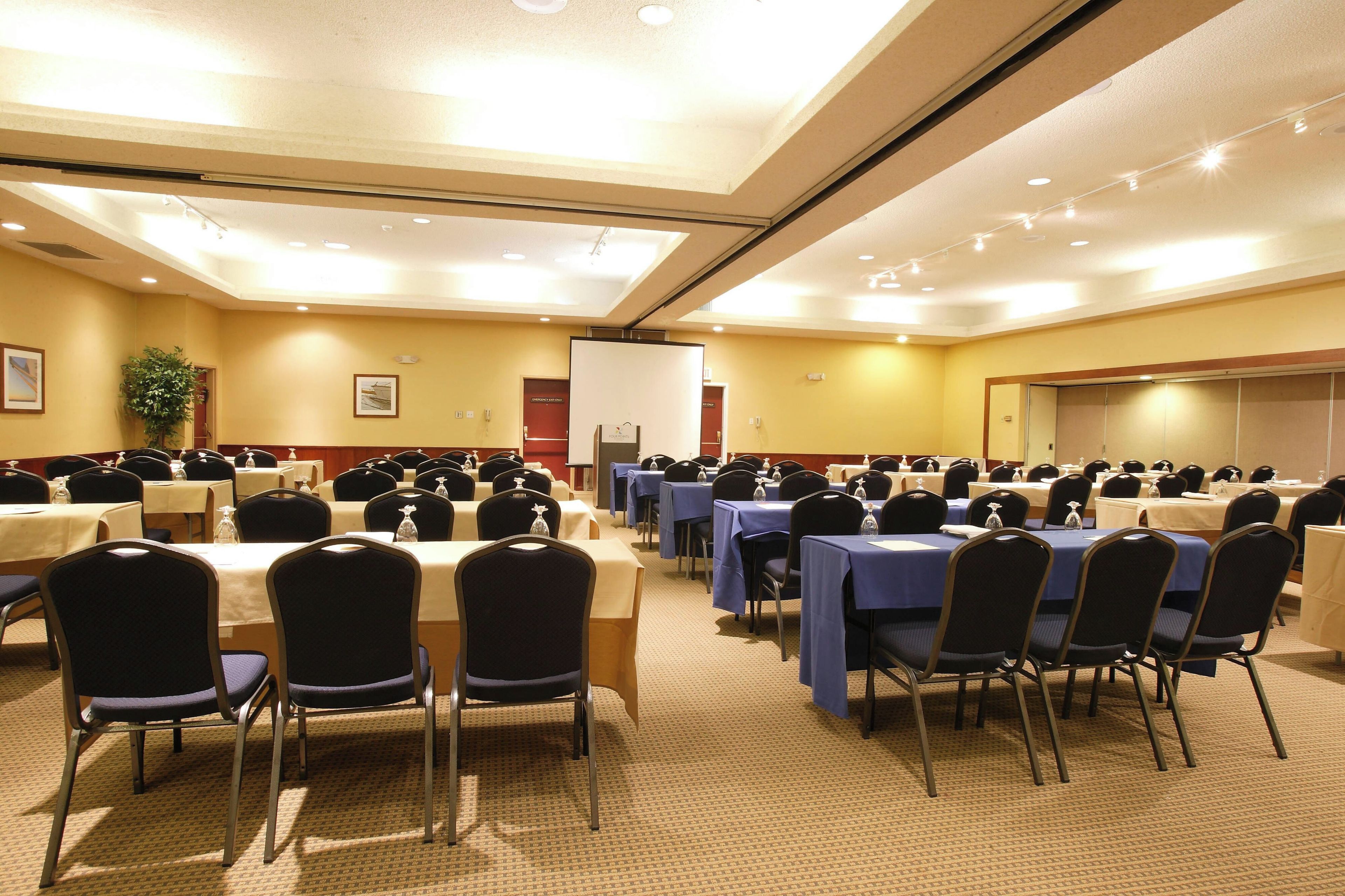 A conference room with multiple tables and chairs, equipped with nameplates and water bottles.