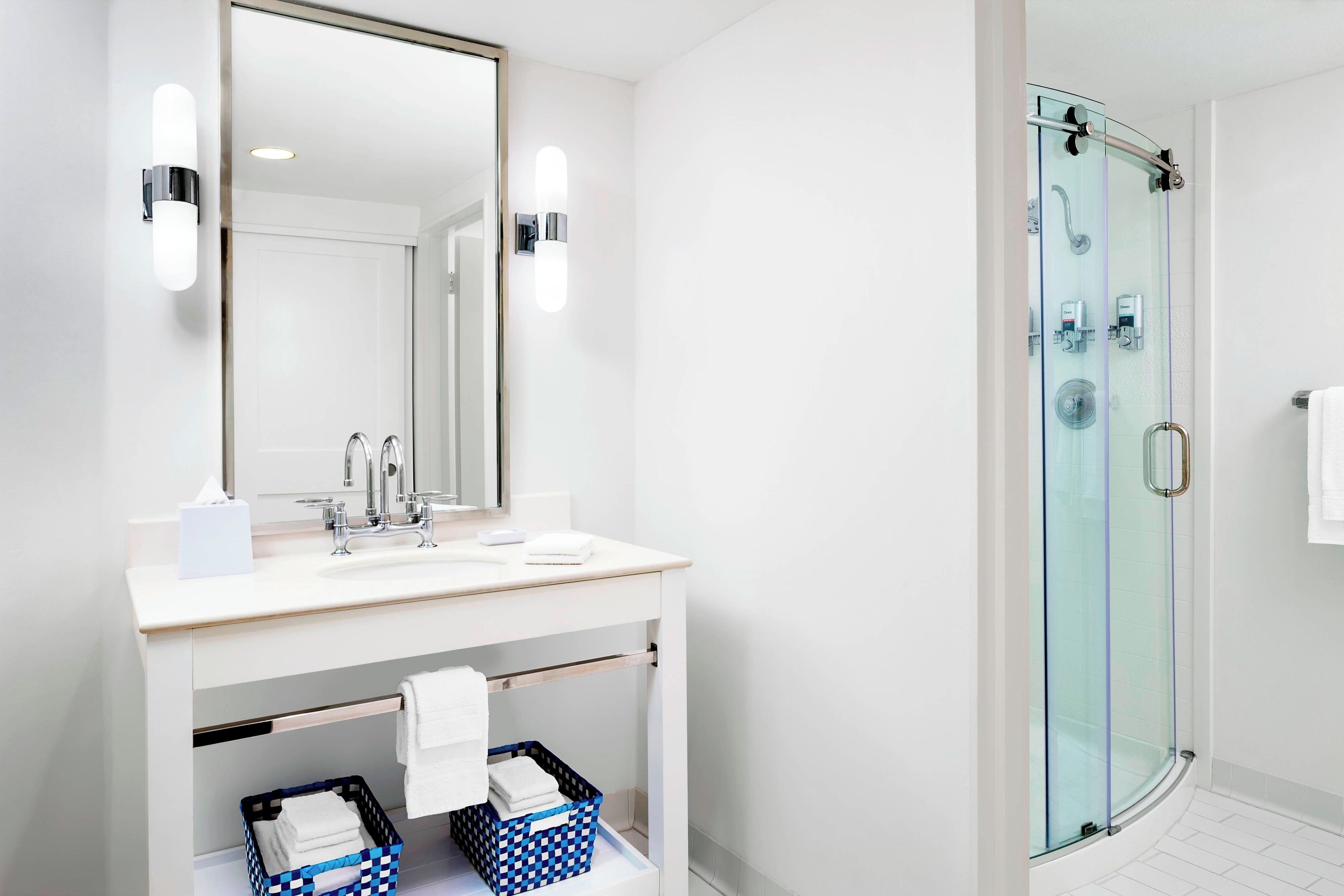 A modern bathroom with a glass shower enclosure, a double sink vanity, and a large mirror.