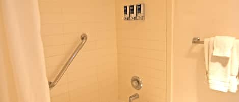 A bathroom with a bathtub, a shower curtain, a grab bar, and a towel rack.