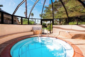 A swimming pool with a glass enclosure, surrounded by tiled walls and a brick border. - Four Points by Sheraton Ventura Harbor Resort (Ventura)