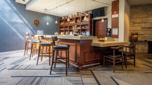 A bar area with a wooden counter, multiple bar stools, and a variety of bottles and glasses on shelves.