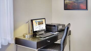 A modern office desk with a computer, printer, and ergonomic chair.