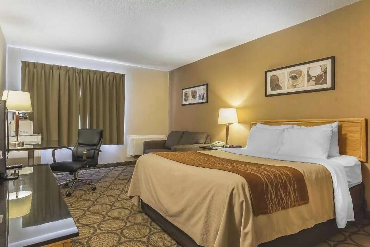 Ein Hotelzimmer mit einem Bett, Schreibtisch, Stuhl und zwei Lampen.